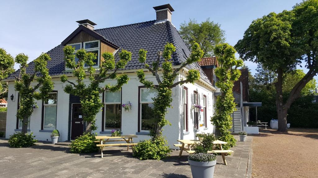 ein Haus mit einem Tisch und Bänken davor in der Unterkunft Herberg Boswijck, B&B in Wijckel