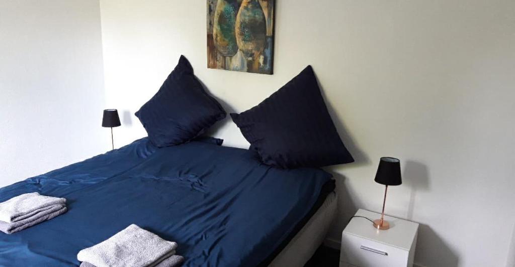 a bedroom with a bed with blue sheets and pillows at Villa Wolte Bed and Breakfast in Ringsted