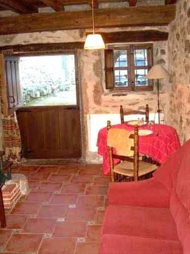 a living room with a table and a red couch at La Plazuela in Navalguijo