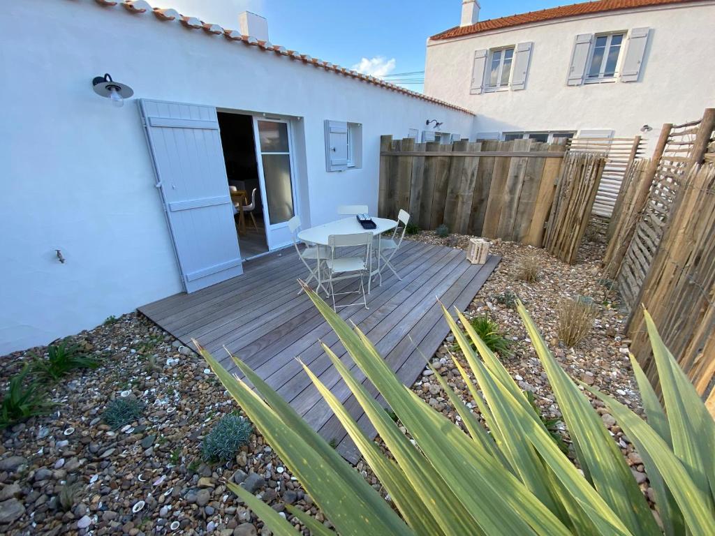 eine Holzterrasse mit einem Tisch und einem Zaun in der Unterkunft Appartements Les Homards du Fier #3 in La Guérinière