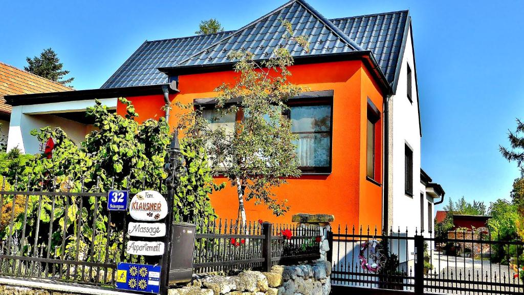 ein orangenes Haus mit einem Zaun davor in der Unterkunft Appartements Regina in Mörbisch am See