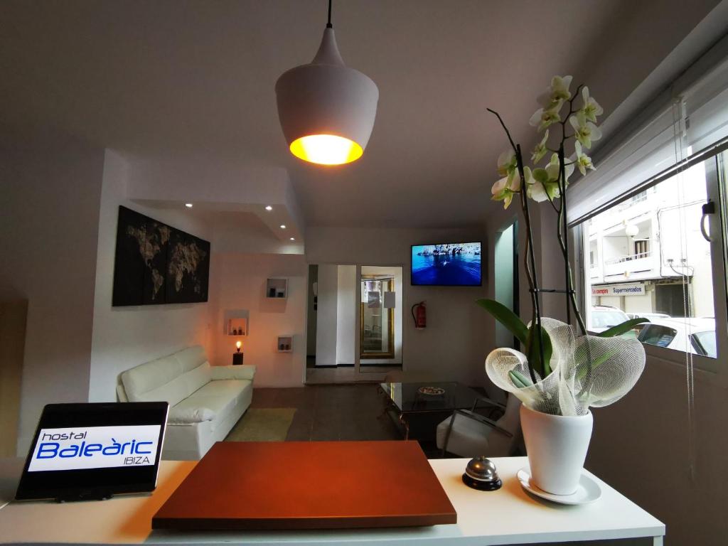ein Wohnzimmer mit einem Sofa und einem Tisch mit einem Laptop in der Unterkunft Hostal Baleàric in Sant Antoni de Portmany