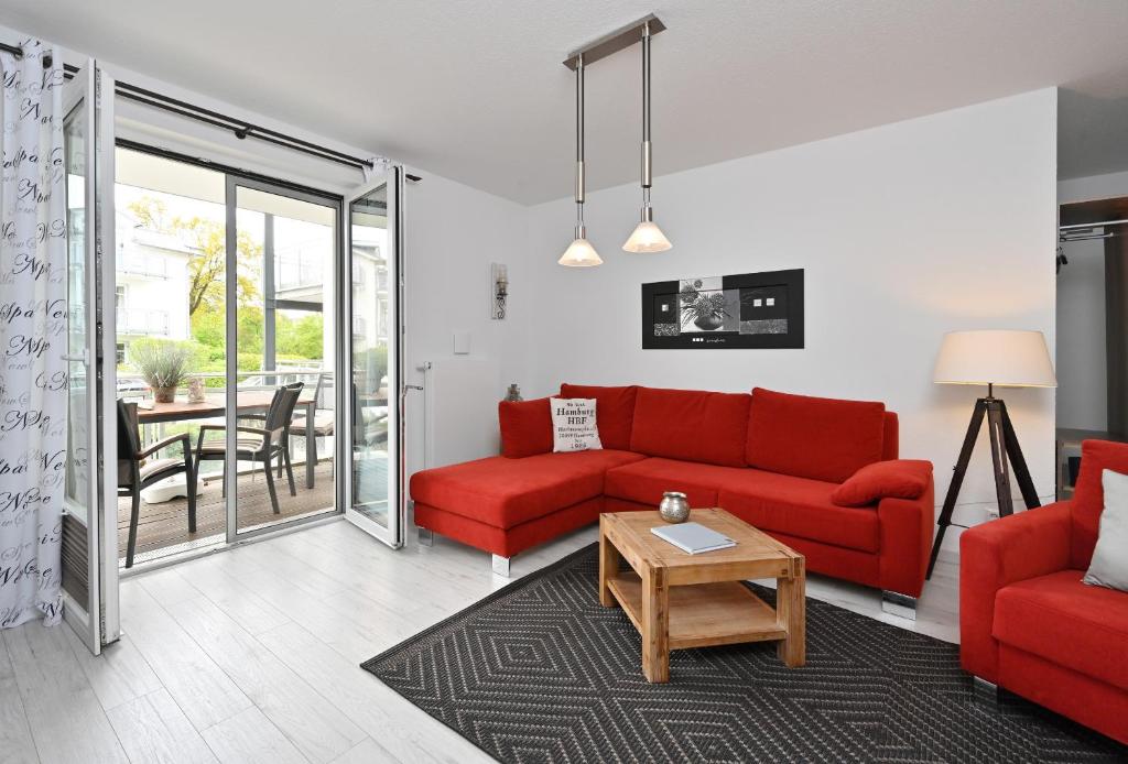 a living room with a red couch and a table at Ferienwohnung Badestrand in Juliusruh