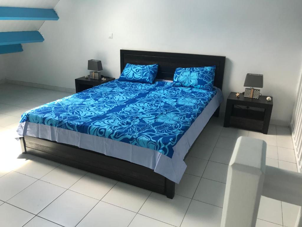 Schlafzimmer mit einem Bett mit blauer Bettwäsche und blauen Kissen in der Unterkunft FRAICHEUR DES CARAIBES in Saint Martin