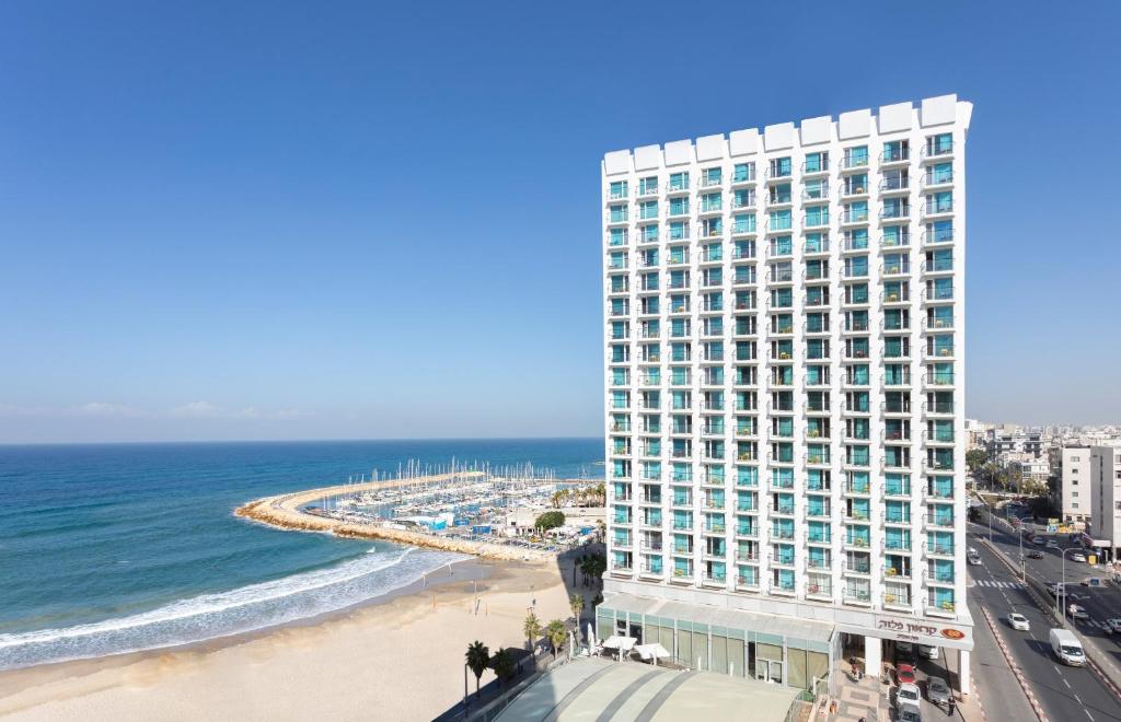 un alto edificio vicino a una spiaggia e all'oceano di Crowne Plaza Tel Aviv Beach, an IHG Hotel a Tel Aviv