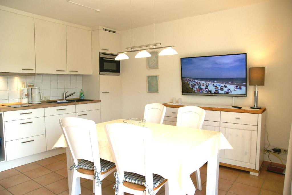 a kitchen with a table with white chairs and a tv at Ferienwohnung 7 Katharina mit Balkon in Lauterbach