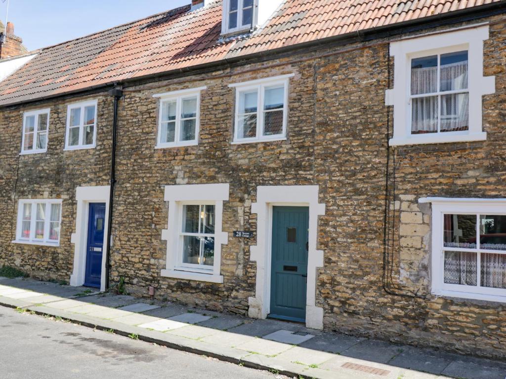 an old brick house with a blue door and white windows at Troopers Cottage in Frome