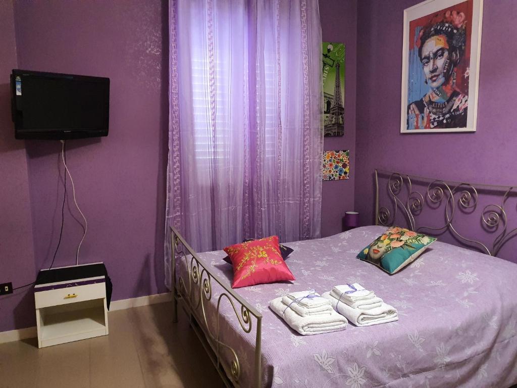 ein lila Schlafzimmer mit einem Bett mit Handtüchern darauf in der Unterkunft FRIDA B&B in Massafra