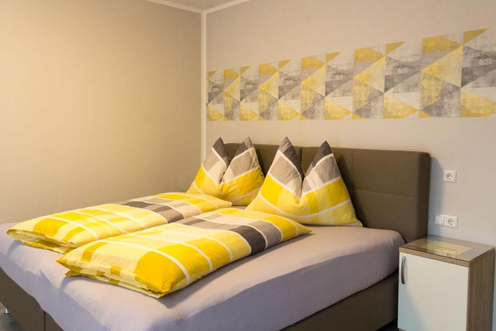 a bed with yellow and white pillows on it at Pension Puster in Gobernitz