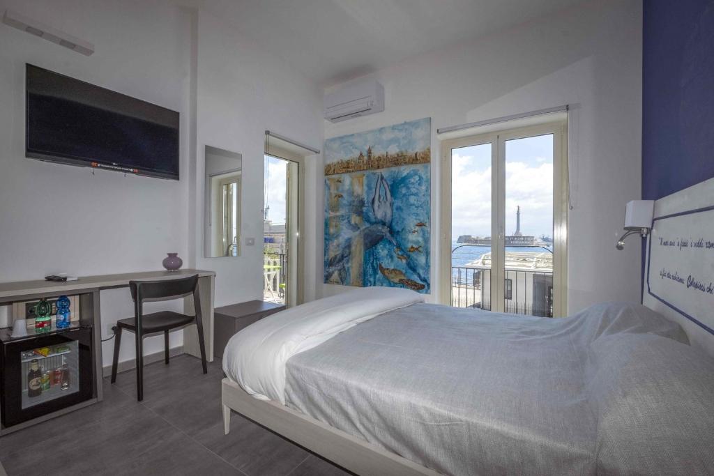 una camera con letto, scrivania e finestra di Miti Dello Stretto B&B a Messina