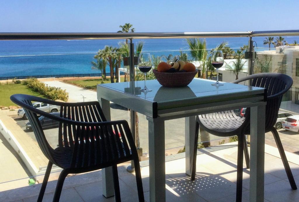 a table with a bowl of fruit and wine glasses on a balcony at Coralli Superior Seaview in Protaras