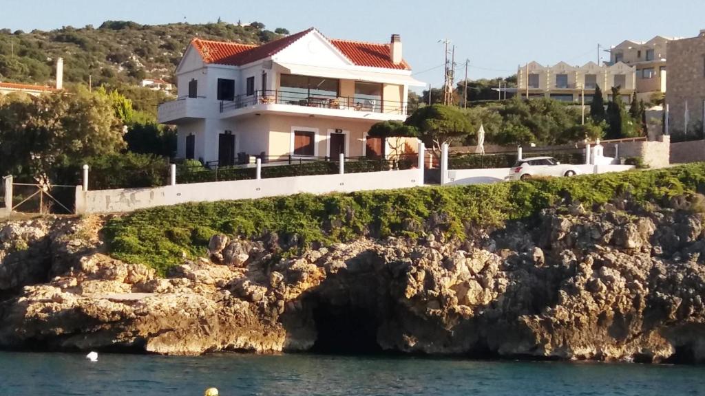 a house on a cliff next to the water at Ostria Seaside Home in Almirida