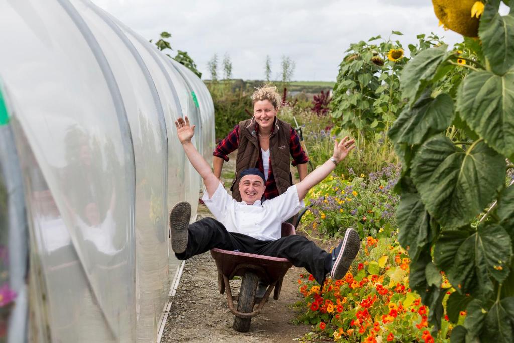 two people jumping in a wheelbarrow in a garden at Dunmore House Hotel in Clonakilty