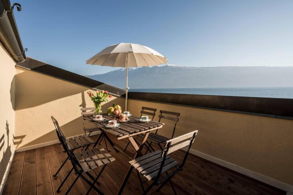 a table and chairs on a balcony with an umbrella at Uliveto - Apartment in olive grove directly on the lake in Gargnano