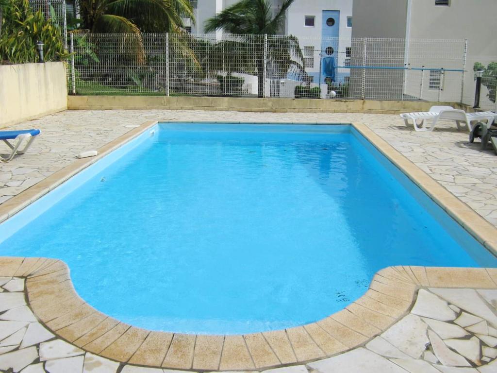a large pool with blue water in a yard at Maison d'une chambre avec vue sur la mer piscine partagee et jardin clos a Les Trois Ilets in Les Trois-Îlets