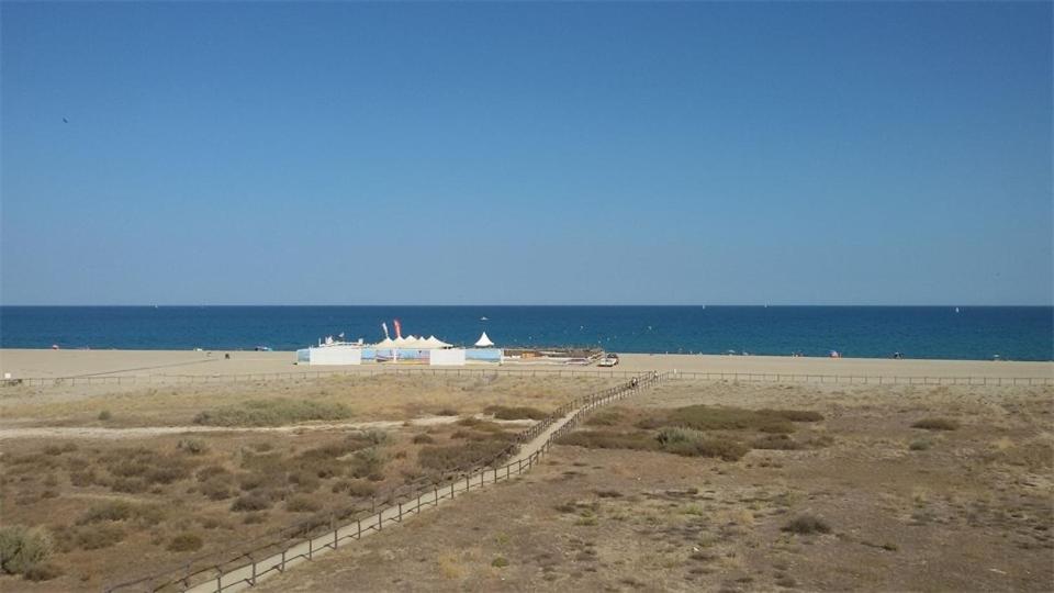 einen Zaun am Strand mit dem Ozean im Hintergrund in der Unterkunft Confortable T2 + Cabine face à la mer 4BALM39 in Le Barcarès