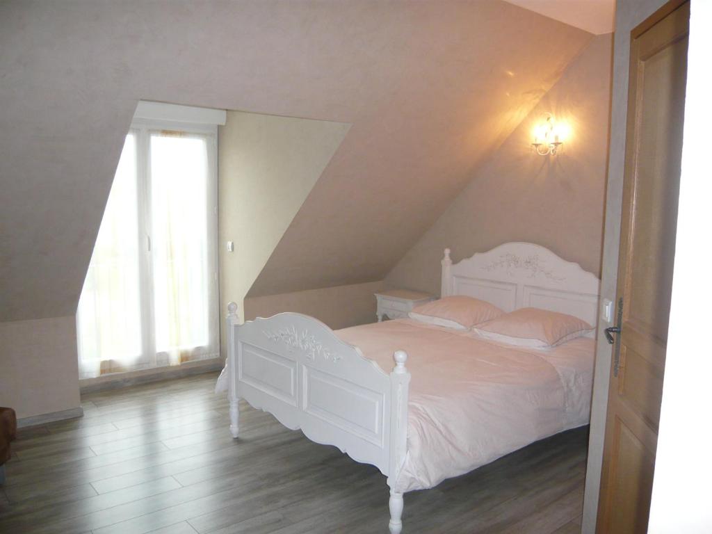 a bedroom with a white bed with pink pillows at Domaine d'Auxonnettes Chambres d'Hôtes et Gîtes in Saint-Fargeau-Ponthierry