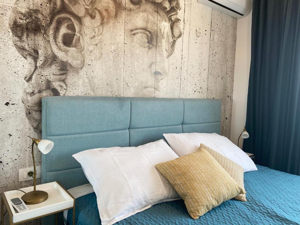 a bed with a blue headboard and a wall at Vista center Apartment in Pula
