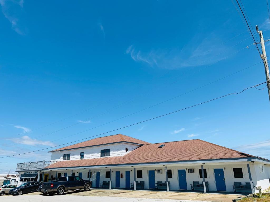 a building with blue doors and cars parked in a parking lot at Sand Dollar Motel in Atlantic Beach