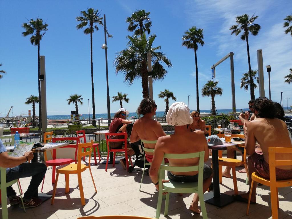 un gruppo di persone seduti ai tavoli sulla spiaggia di Serendipity Mare a Marina dʼAndora