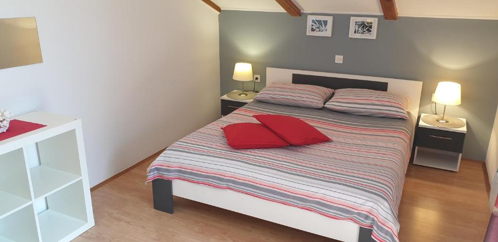 a bedroom with a bed with two red pillows on it at Apatmani Milena in Opatija