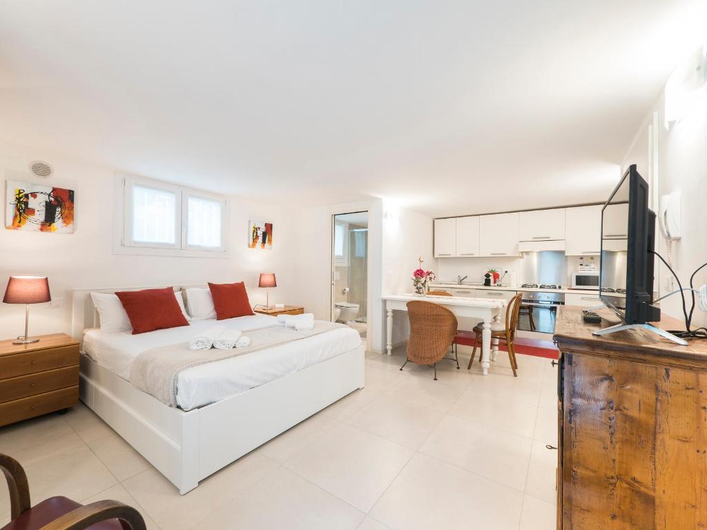 een witte slaapkamer met een bed en een keuken bij Sweet Studio IN GIARDINO in Padua