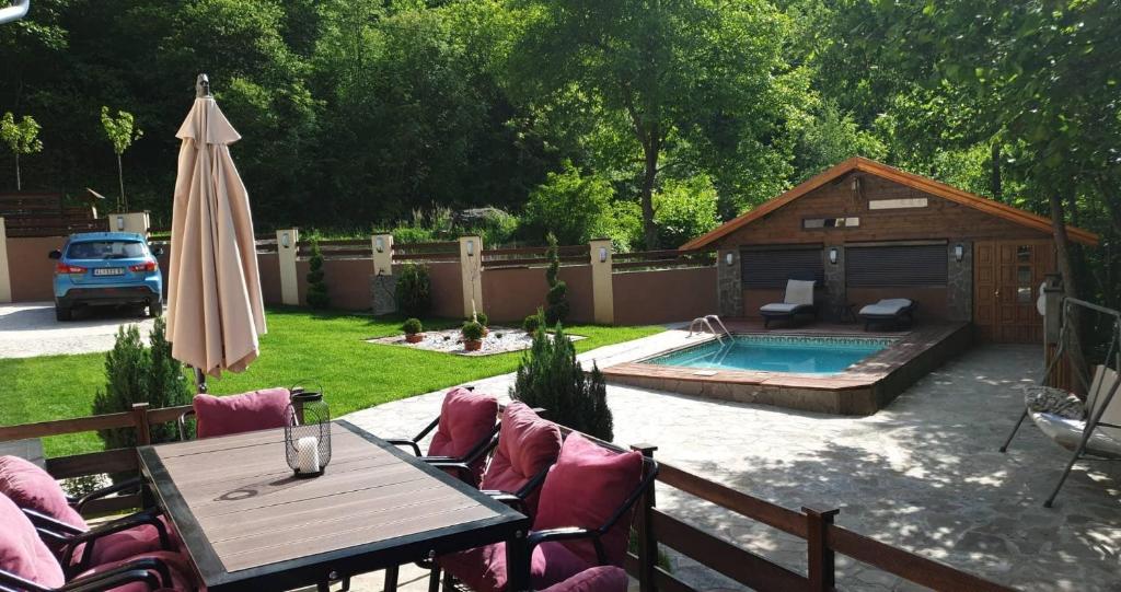a patio with a table and an umbrella and a pool at Lodge Zeleni svet in Crni Vrh