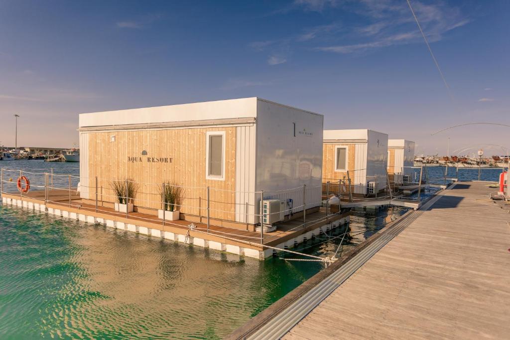 ein Gebäude auf einem Dock neben dem Wasser in der Unterkunft AQUA RESORT GIULIANOVA - Houseboat Experience in Giulianova