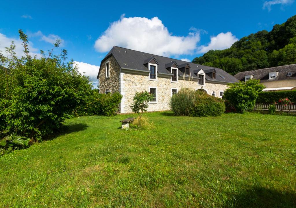 ein großes Steinhaus auf einem Grasfeld in der Unterkunft La Ferme de Couty in Saint-Pé-de-Bigorre