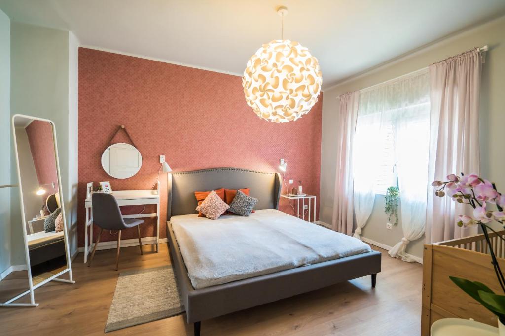 1 dormitorio con cama, escritorio y lámpara de araña en Helka Ház, en Siófok
