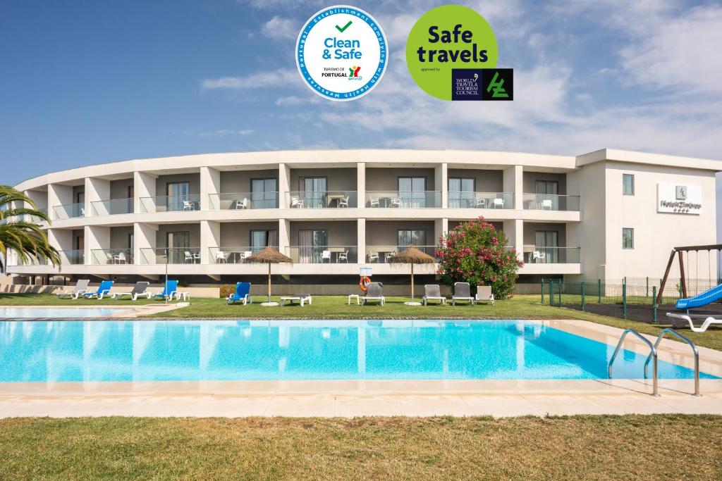 a hotel with a pool and a sign that says safe travels at Hotel dos Zimbros in Sesimbra