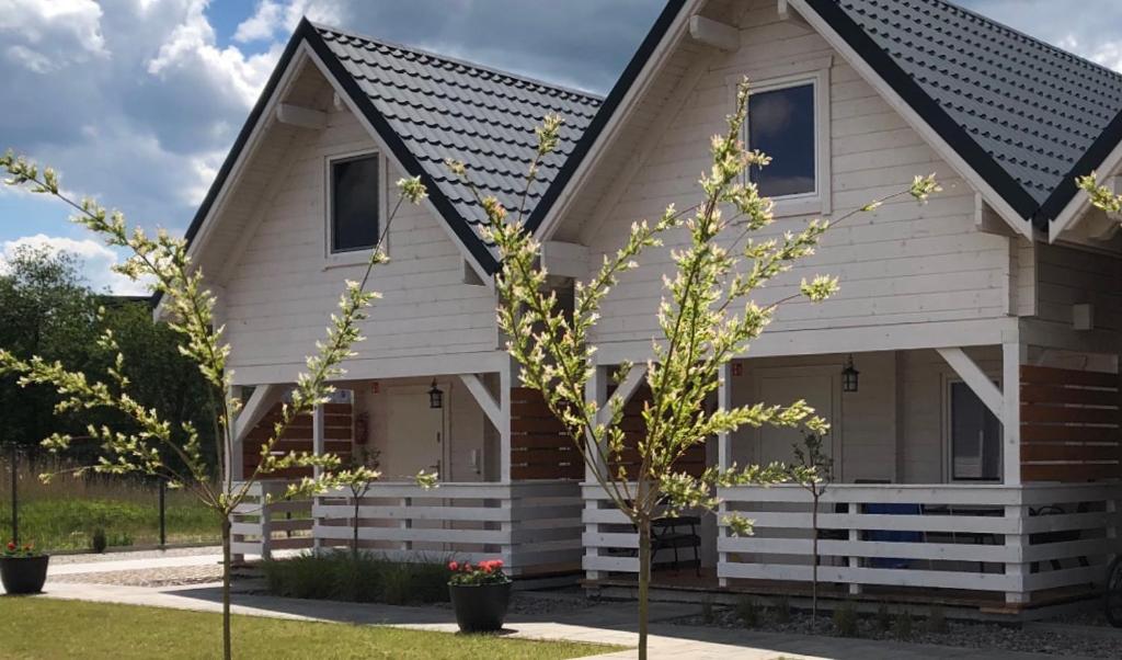 a white house with a black roof at Merinn in Rogowo