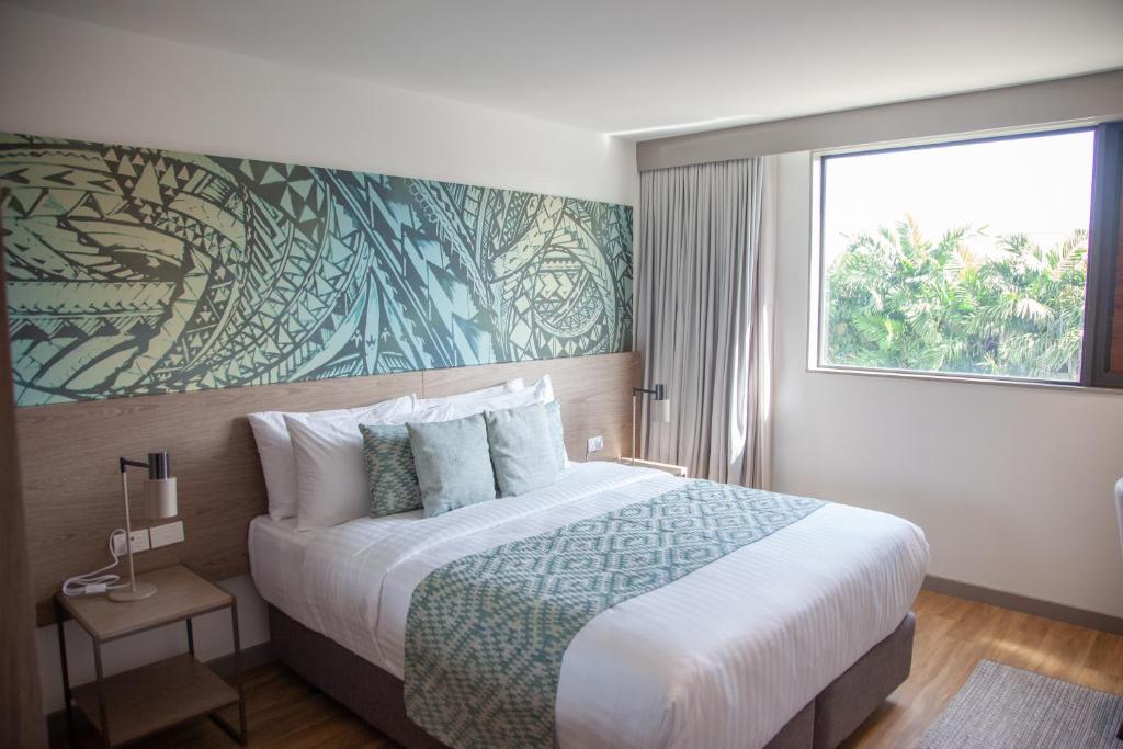 a bedroom with a large bed with a large window at Lava Hotel in Apia