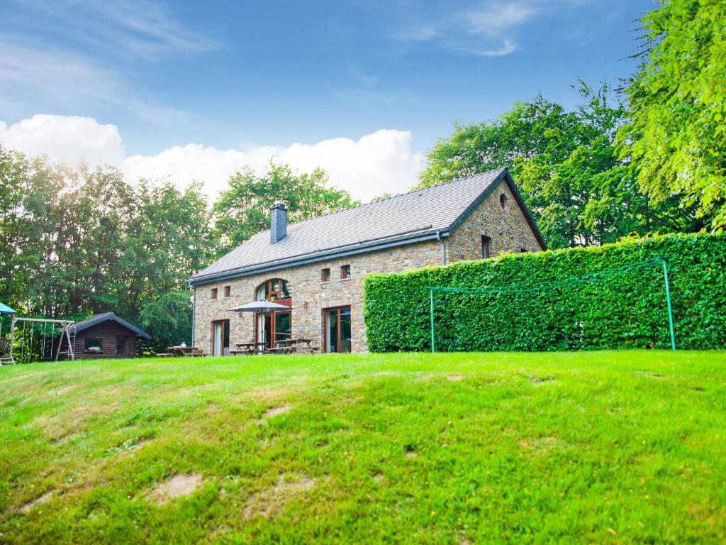 a stone house with a hedge in front of a yard at Lavish Holiday Home in Malmedy with Sauna in Longfaye