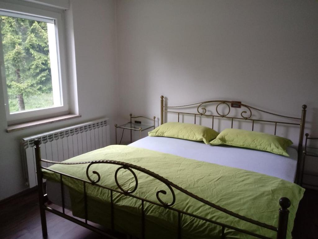 een slaapkamer met een bed met groene lakens en een raam bij Apartmaji Velikonja in Ajdovščina