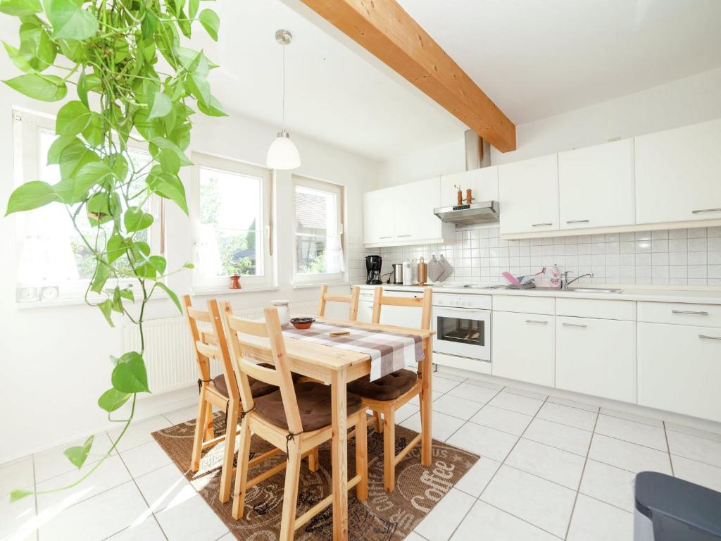 a kitchen with white cabinets and a wooden table and chairs at Apartment in Densberg with terrace in Densberg