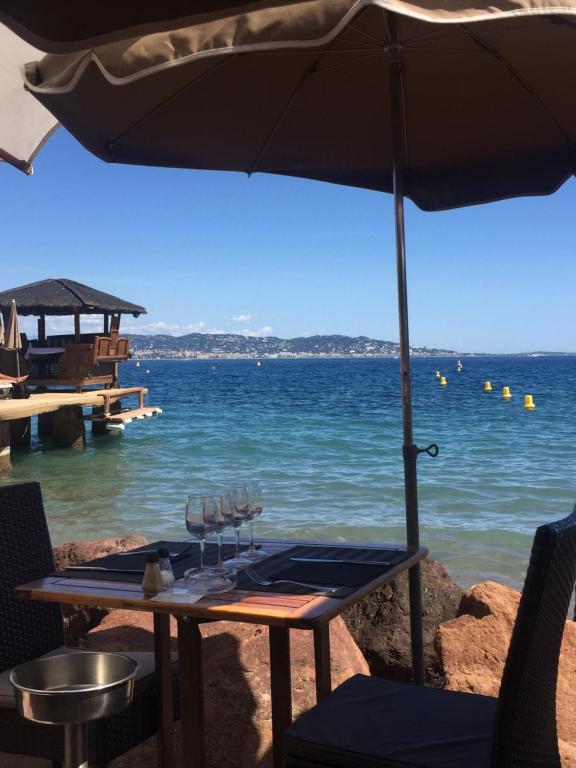 stół z parasolem obok wody w obiekcie Studio au cœur de Théoule w mieście Théoule-sur-Mer