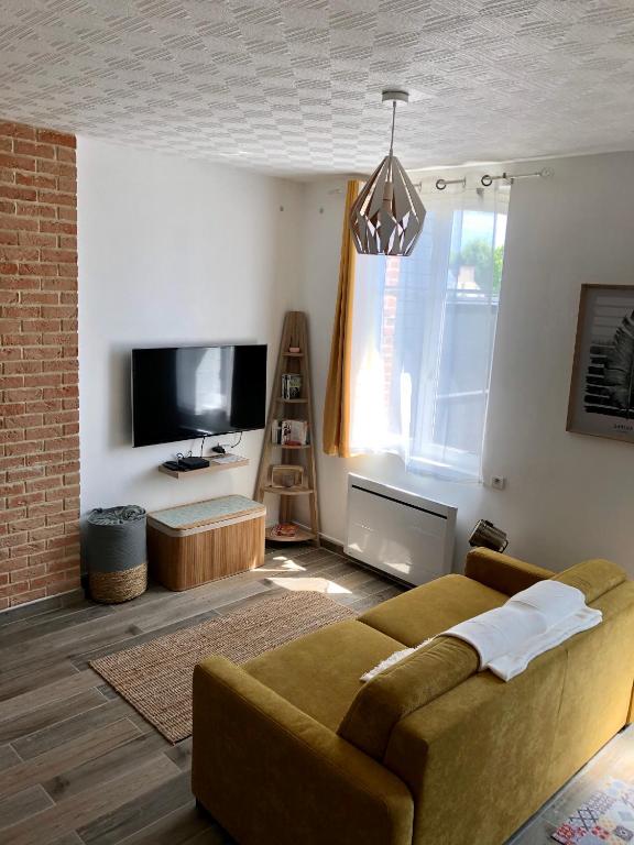 un salon avec un canapé et une télévision dans l'établissement Les jardins d Honfleur et sa terrasse privative, à Honfleur