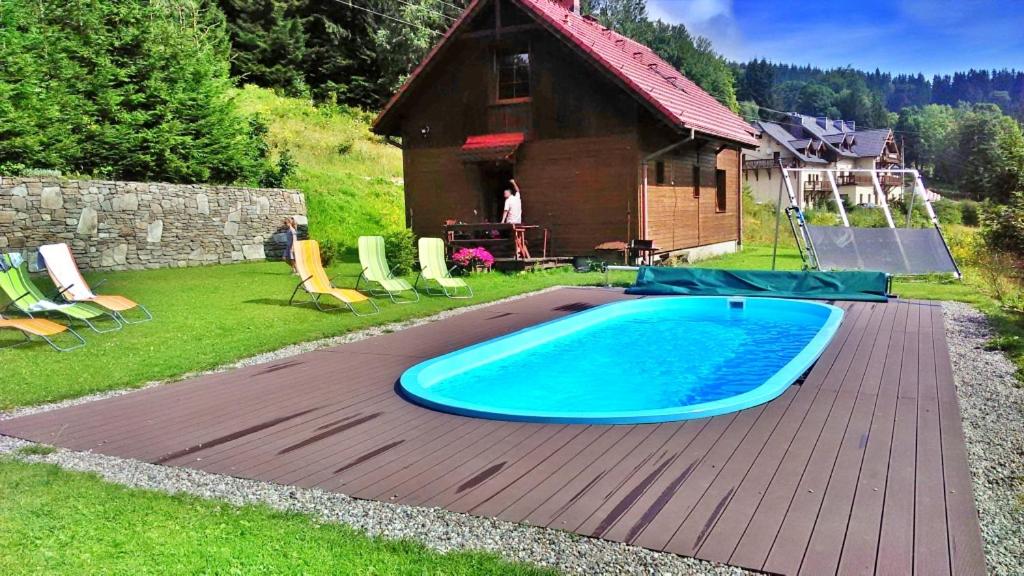 a swimming pool on a wooden deck next to a house at Domek Górski Czarna Góra w Siennej in Stronie Śląskie