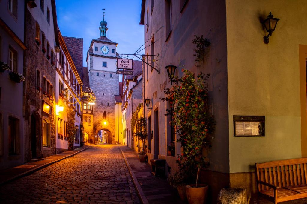 eine Gasse mit einem Gebäude mit einem Uhrturm in der Unterkunft Gästehaus am weißen Turm in Rothenburg ob der Tauber