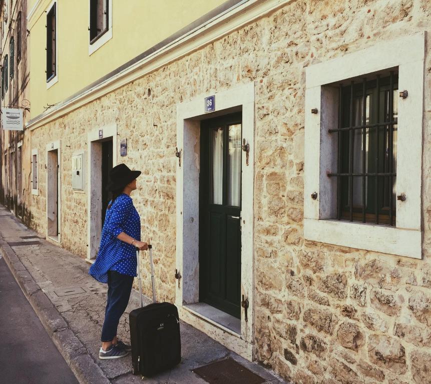 une femme debout à côté d'un bâtiment avec une valise dans l'établissement River-view studio perfect for travelers, à Metković
