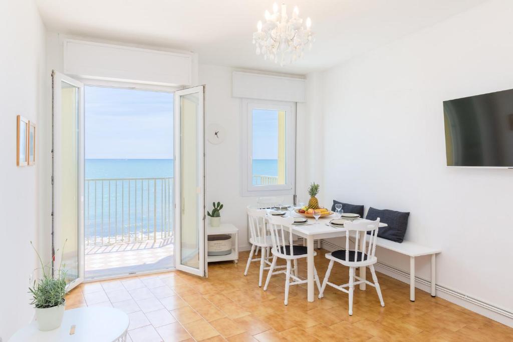 una sala da pranzo bianca con tavolo e vista sull'oceano di Appartamento in posizione centrale con vista mare e parcheggio a Caorle