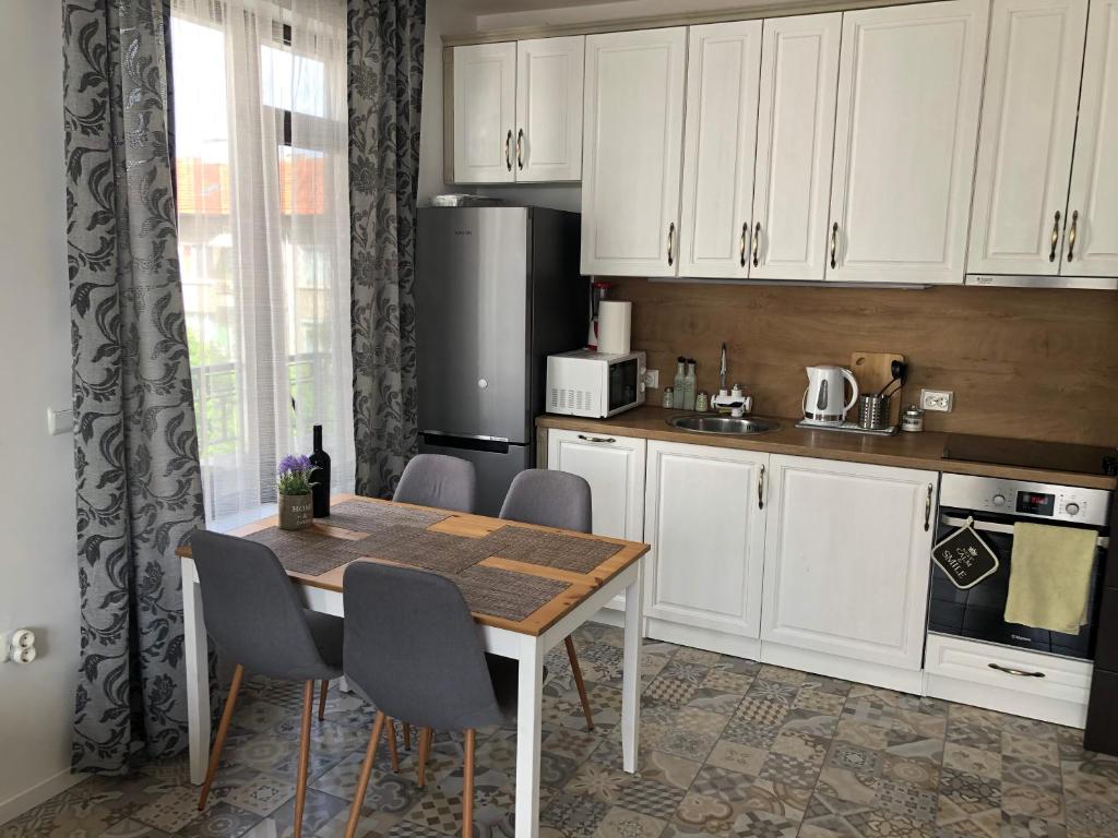 eine Küche mit weißen Schränken und einem Tisch und Stühlen in der Unterkunft Sunny Shore Burgas Apartment in Burgas City