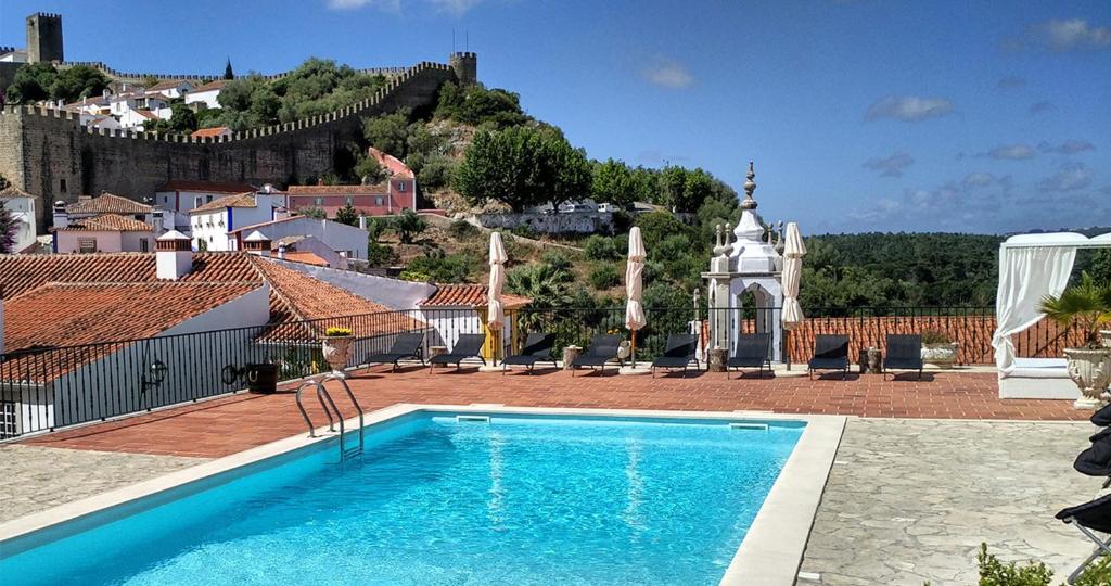 a swimming pool in front of a building with a castle at Hotel Real d Obidos in Óbidos