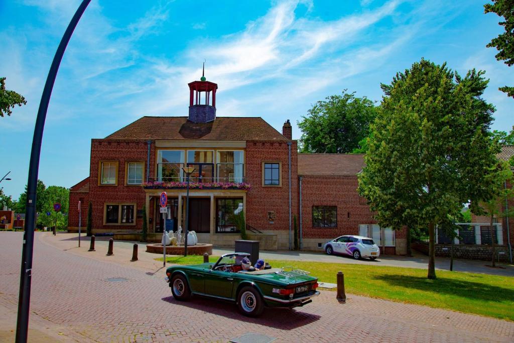 a green car parked in front of a building with a lighthouse at Atalanta-Wellness Roermond 'de Archivaris' in Herten