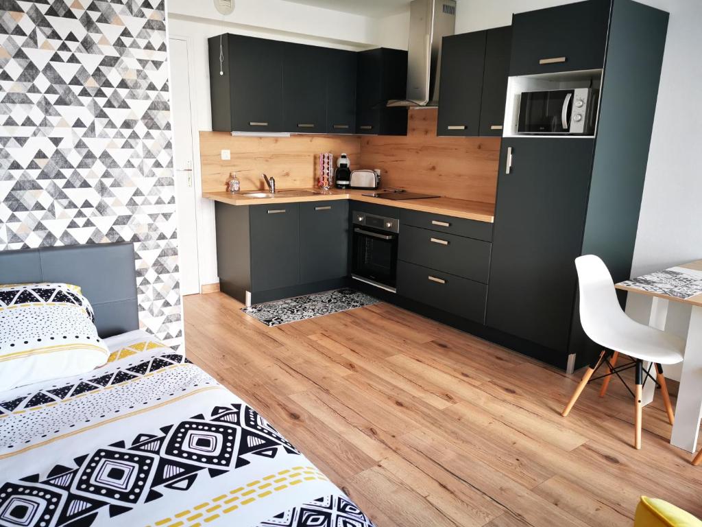 a kitchen with black cabinets and a table and a bed at Studio Cosy Breizh in Cancale