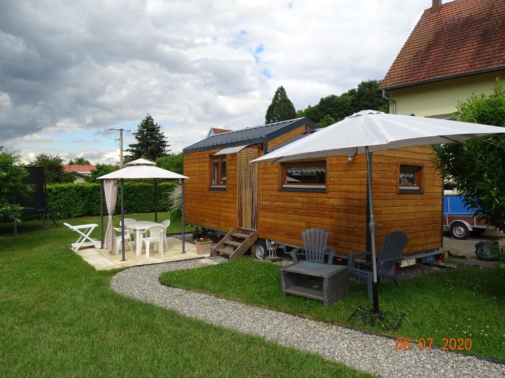 a wooden cabin with an umbrella and a table and chairs at Tiny-house in Wihr-au-Val