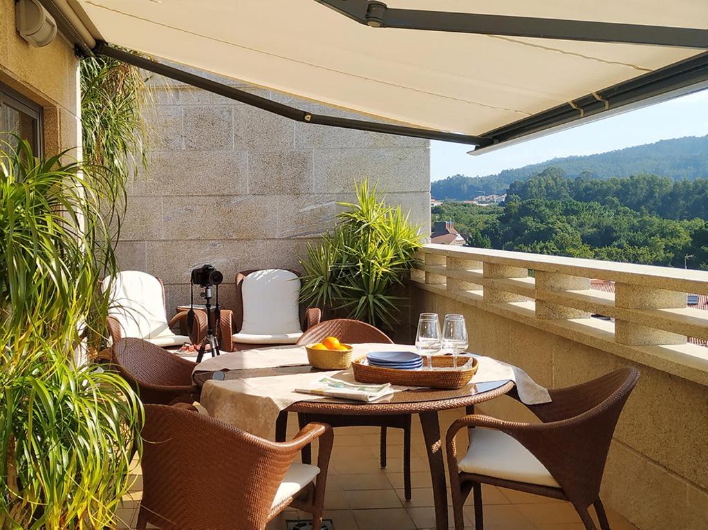 eine Terrasse mit einem Tisch und Stühlen auf dem Balkon in der Unterkunft Lujoso ático en Sanxenxo in Sanxenxo