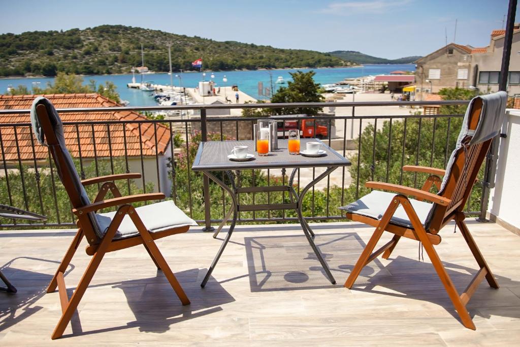 a table and two chairs on a balcony with a view at Kaprije apartmani Tina i Ena in Kaprije