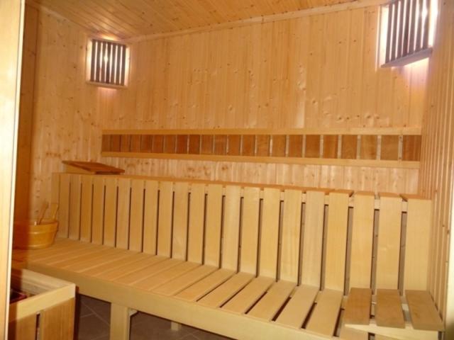 un banco de madera en una habitación con 2 ventanas en Detelina Complex, en Hisarya
